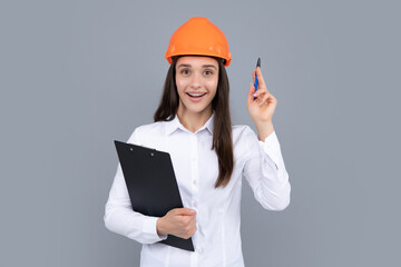 Surprised shocked excited business woman with clipboard, portrait on gray. Young woman in helmet hold laptop computer on gray background. Architect businesswoman.