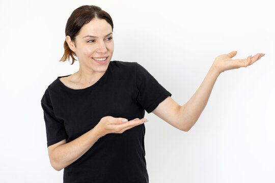 Happy woman presenting product against white background. Cheerful Caucasian woman holding invisible object on her palms, posing for camera and smiling. Emotion, gesture, presentation concept