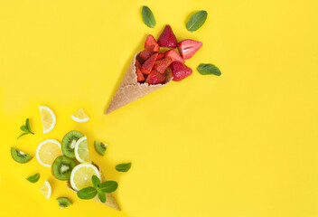 Ice cream cone with fruit and berry on the yellow background. Copy space. Top view.