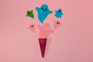 pink cornet from which colorful ghosts fly on a pink background, creative art halloween concept, flat lay, paper craft ghost

