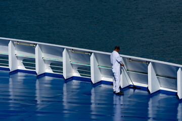 man in white coveralls cleaning ship deck