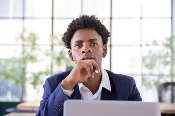Portrait of concentrated male office worker. Focused businessman looking up, touching chin, holding pen. Business, office work concept.