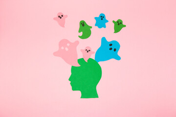green paper head from which colorful spirits fly, possessed head, halloween creative concept, flat lay, paper craft
