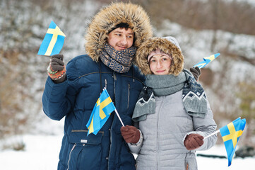 Scandinavian couple with Sweden flag in winter swedish landscape.