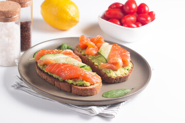 Two tasty open salmon sandwiches with avocado and cucumber. Morning healthy breakfast. Top view.