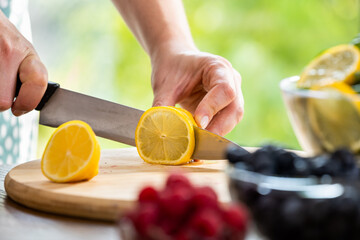 Woman cutting lemon and preparig juice from fruits