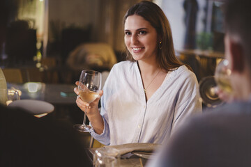 Beautiful young lady carefree enjoying a glass of white wine in an elegant restaurant on a weekend...
