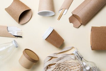 Naklejka premium Eco-friendly packaging and utensils around a paper cup for coffee on a yellow background. The concept of ecology and zero waste.