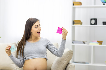 Photo of positive pregnant woman holding pink and blue papers