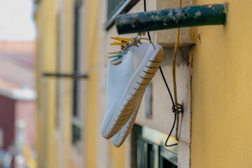 White shoe on the washing line in city with cement wall as background, Hanging clothes on the clothesline outside building, Typical Portuguese style drying laundry under the sun in summer, Portugal.