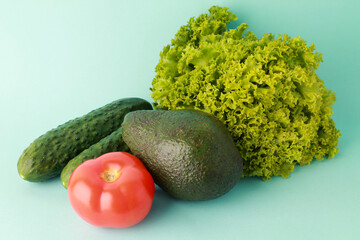 Fresh vegetables on green color background. Cucumber tomato avocado salat. Healthy food concept background. Vegan vegetarian food diet clean eating