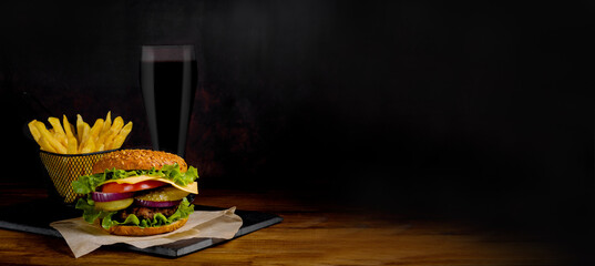 Delicious burger, french fries and a drink. Banner, billboard. Dark background. Vintage.
