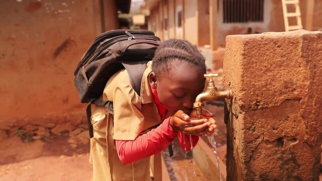 A Student Drinks Water From A Public Fountain In Africa, A Concept Of Drought And Water Scarcity In Africa.