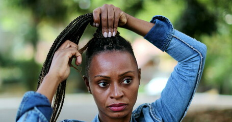 African woman adjusting dread hair outside