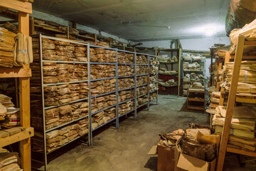 Room of an abandoned soviet administrative building with old archival paper documents on racks in...