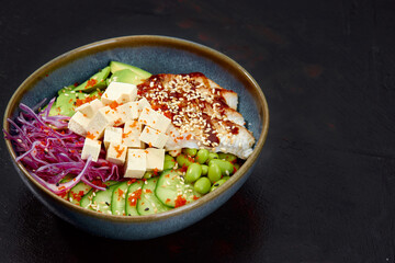 Salad with eel, avocado and herbs in the plate on black background
