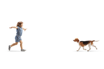 Full length profile shot of a happy little girl running to hug a dog