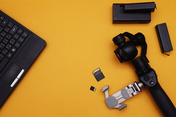 Fototapeta premium action camera with a miniature mechanical stabilizer and a laptop on an orange background.
