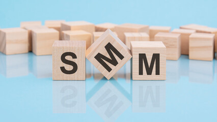 SMM. wooden cubes. blocks lie on a black background. stacks with coins. inscription on the cubes is reflected from the surface of the table. selective focus. SMM - Social Media Marketing