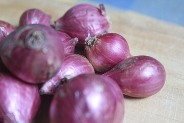 a bunch of red onions on a wooden board