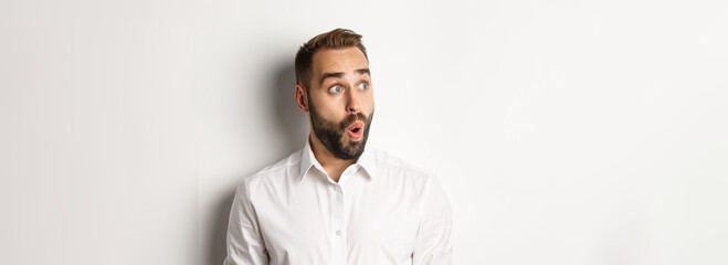 Close-up of happy and surprised man looking left with amazed face, white background