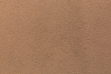 Sample of a texture of brown plaster. Wall finished with a decorative cement stucco. Example of exterior building decoration. Clean uniform grainy background. Banner. Wallpaper. Copy space. Pattern