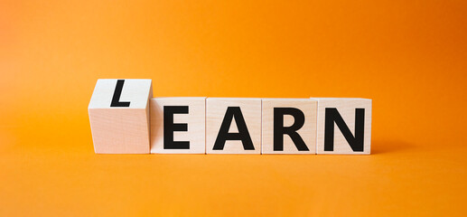 Learn or earn symbol. Turned wooden cubes with words Earn and Learn. Beautiful orange background. Business Earn and Learn concept. Copy space.