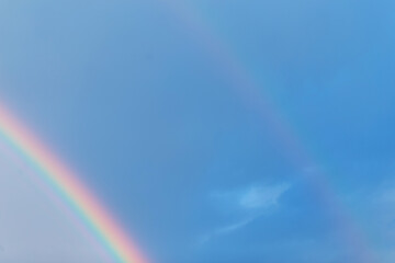 Amazing colorful double rainbow in the blue sky on a rainy day