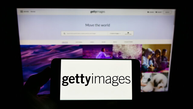 Stuttgart, Germany - 12-12-2021: Person holding smartphone with logo of stock photo provider Getty Images Inc. on screen in front of website. Focus on phone display.