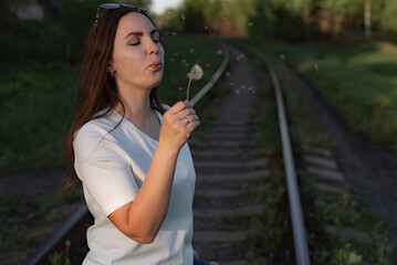 woman blowing on a dandelion. portrait of a woman.