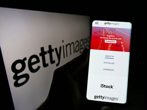 Stuttgart, Germany - 12-12-2021: Person holding cellphone with webpage of stock photo provider Getty Images Inc. on screen in front of logo. Focus on center of phone display.