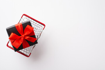 Black friday concept. Top view photo of giftbox with red ribbon bow in shopping cart on isolated white background with copyspace