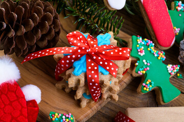 Snowflake-shaped Christmas gingerbread and butter cookies with fir branches and Christmas decorations on a cutting board on wooden background. Christmas background, close up