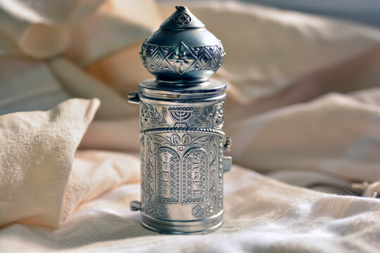 A small Torah scrolls A silver antique with a tour of the tablets of the covenant with the Hebrew letters. placed on a tallit