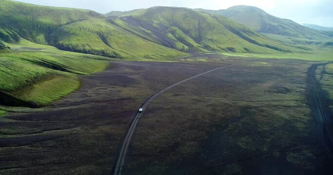 Long shot of a car driving on small road through a plain in Iceland.
