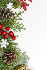 Christmas tree branches, conifer cones and red berries top view with copy space on white background. Christmas, winter holiday, new year concept.	