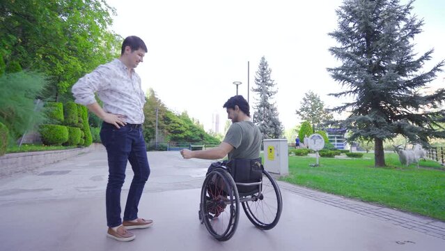 Happy young man in wheelchair having fun with his friend.
The two friends are laughing and having funny moments.
