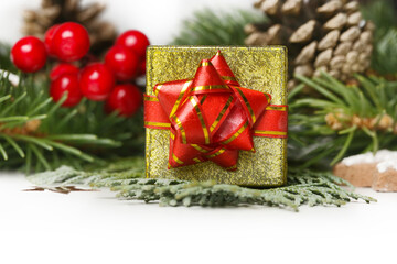 Fototapeta na wymiar Small golden gift box with red bow and Christmas decoration, close up.