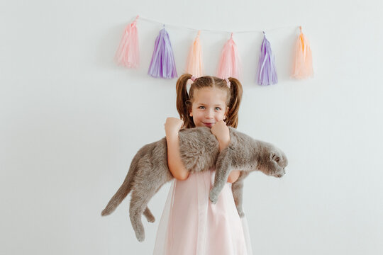 Happy little girl with grey cat, party decoration.Tassel paper garland. White background.