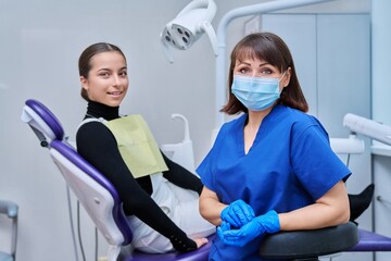 Fototapeta na wymiar Portrait of female dentist with girl patient sitting in dental chair