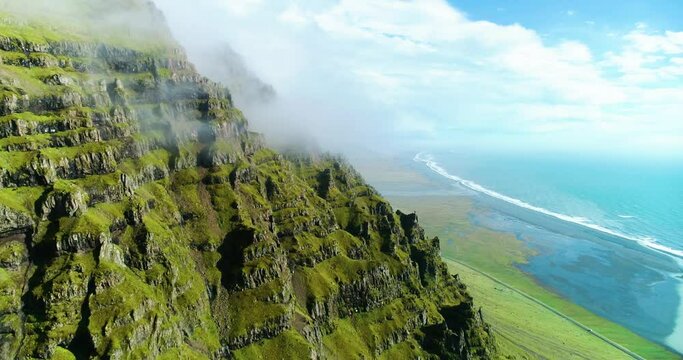 Sky scraping mountain top touches the clouds right next to the sea.