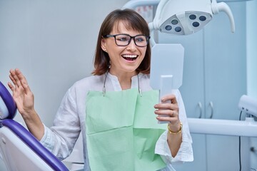 Middle-aged female in dental office looking in mirror