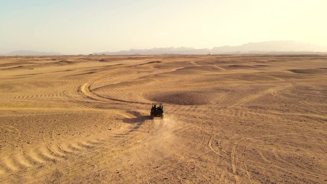 An aerial shot of a buggy vehicle moving in the desert.
