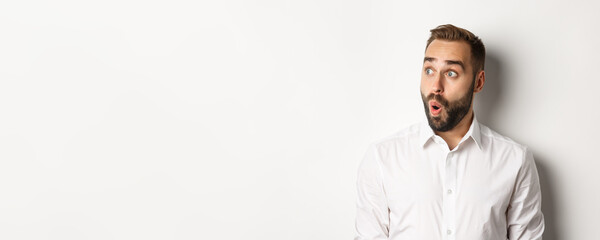 Close-up of happy and surprised man looking left with amazed face, white background