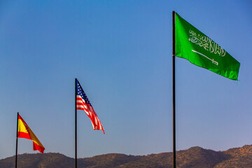 The national flag of saudi arabia and united state of america waving in a blue sky
