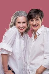 Two cute mature women standing together and hugging