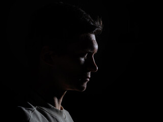 profile of thoughtful man looks to the right. portrait in side light, hard light, photo on black, looks down