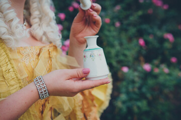 Female hand holding luxurious medieval bottle with perfume, close up, selective focus. Baroque...