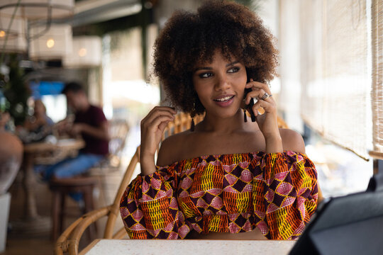 Young African woman talking on mobile phone in a restaurant.