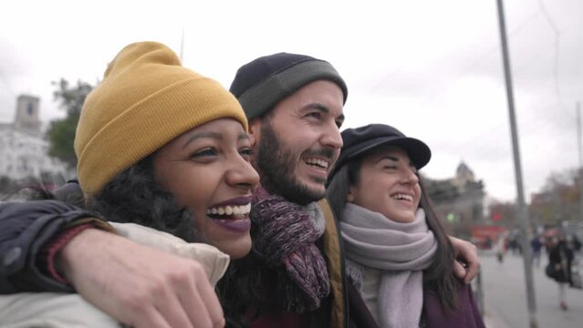 close up of Happy multiracial friends hugging in London. Friendship concept with multicultural young people on winter clothes having fun together. 